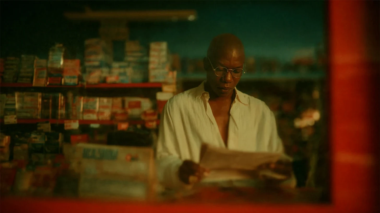 Frame do filme: um comerciante lendo o jornal atrás do balcão, no cotidiano da loja.